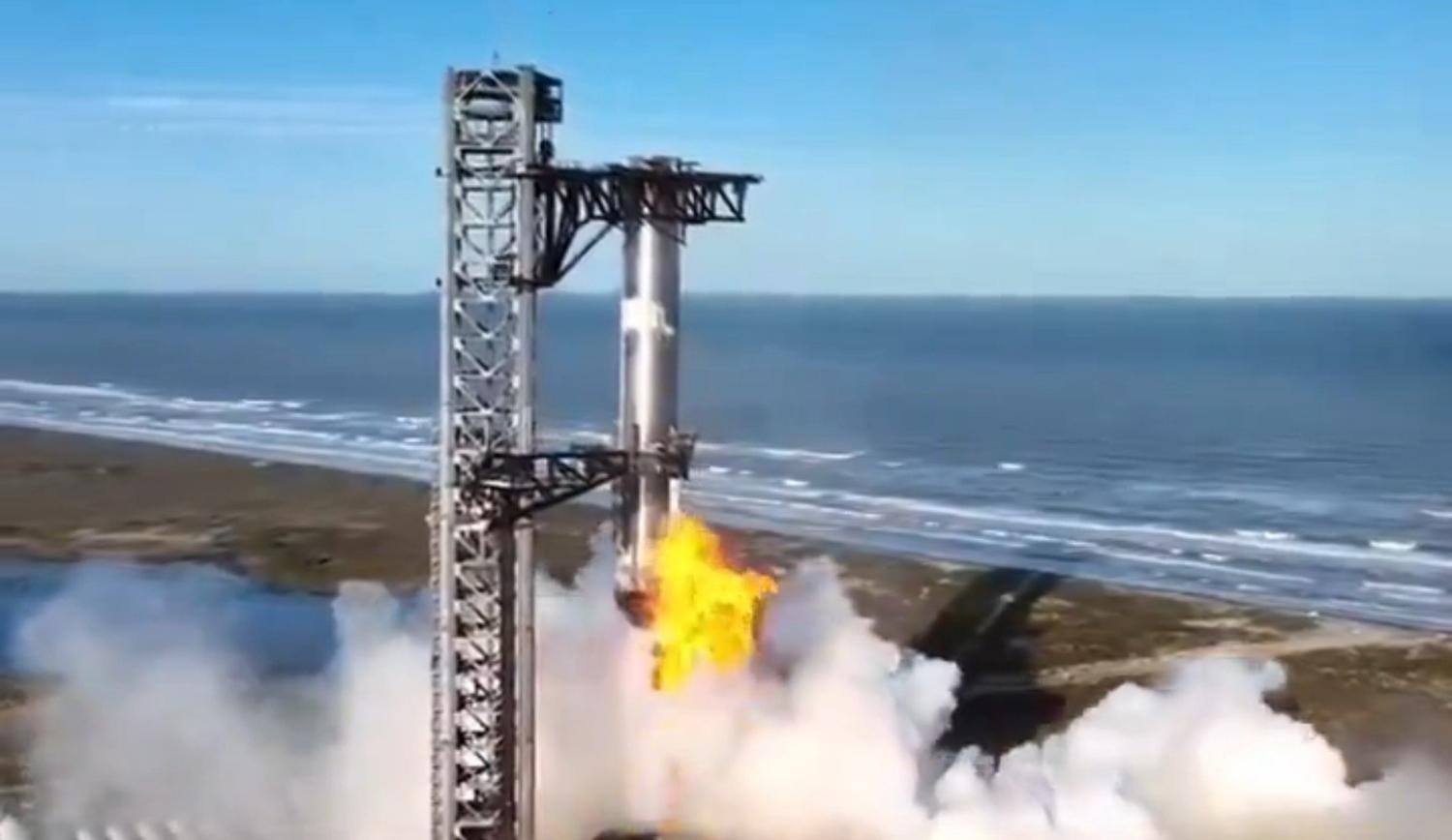 Starship on the tower at the coast, engines lit